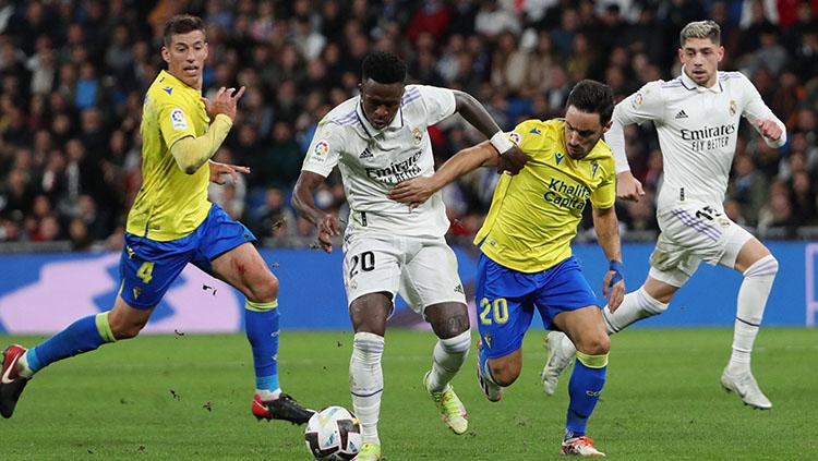 Penyerang Real Madrid, Vinicius Jr berusaha melindungi bola dari rebutan pemain Cadiz di Liga Spanyol. - INDOSPORT