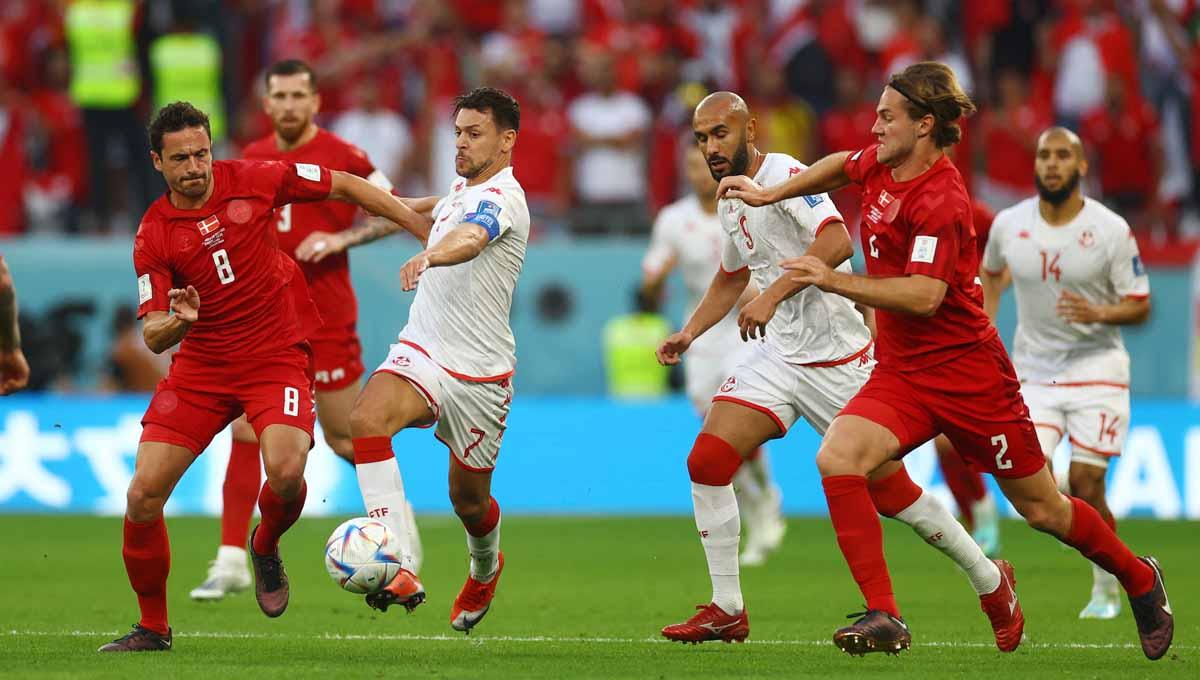 Pemain Denmark, Thomas Delaney dan Joachim Andersen saat berebut bola dengan pemain Tunisia Youssef Msakni dan Issam Jebali di Piala Dunia Qatar 2022. (Foto: REUTERS/Kai Pfaffenbach) - INDOSPORT