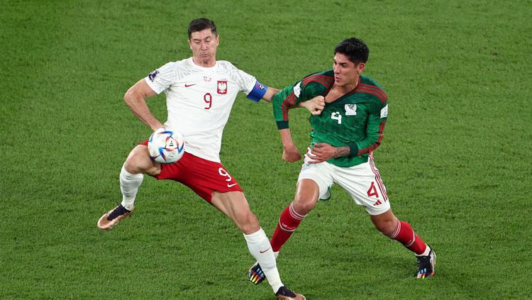 Striker Polandia, Robert Lewandowski (kiri) mendapat pengawalan ketat dari gelandang bertahan Meksiko, Edson Alvarez dalam pertandingan Grup C Piala Dunia 2022 (Foto: REUTERS/Marko Djurica). - INDOSPORT