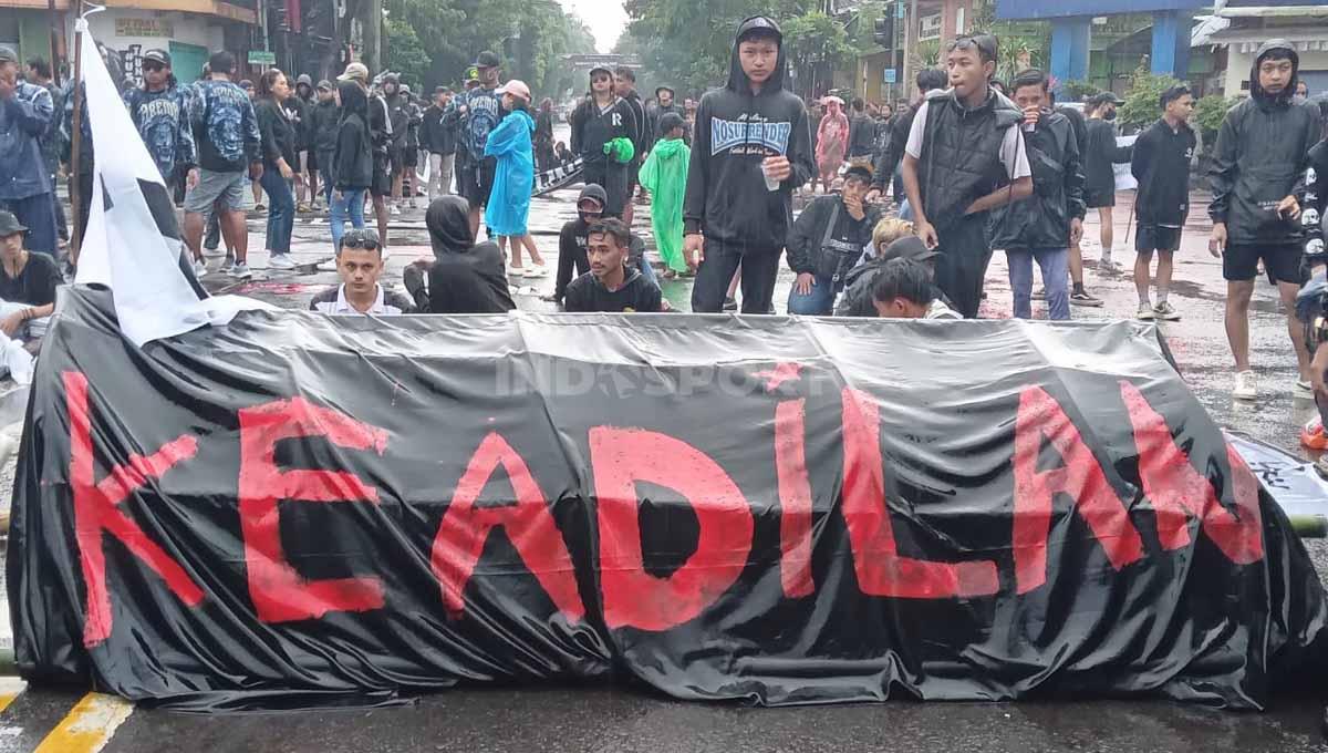 Hujan deras tak menyurutkan arek-arek malang utk terus beraksi turun jalan dlm usut tuntas Tragedi Kanjuruhan.
