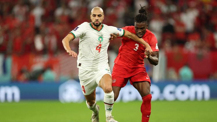 Sofyan Amrabat dari Maroko beraksi dengan Sam Adekugbe dari Kanada di laga Piala Dunia 2022 REUTERS-Carl Recine.jpg - INDOSPORT