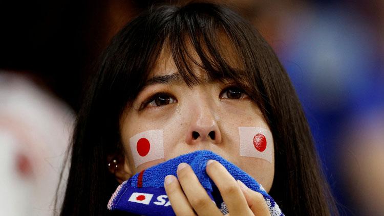 Seorang fans Jepang tak kuasa menahan tangis saat negaranya kalah dari Kroasia di babak 16 besar Piala Dunia 2022 (Foto: REUTERS/John Sibley). - INDOSPORT