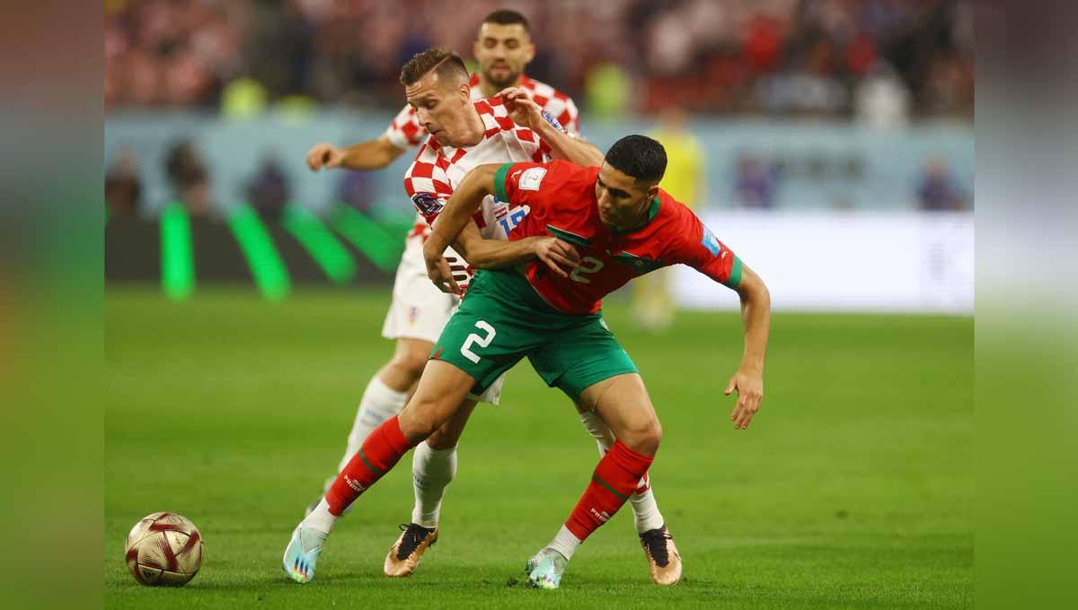 Pemain Maroko Achraf Hakimi berduel dengan pemain Kroasia Mislav Orsic di Piala Dunia Qatar 2022. (Foto: REUTERS/Paul Childs) - INDOSPORT