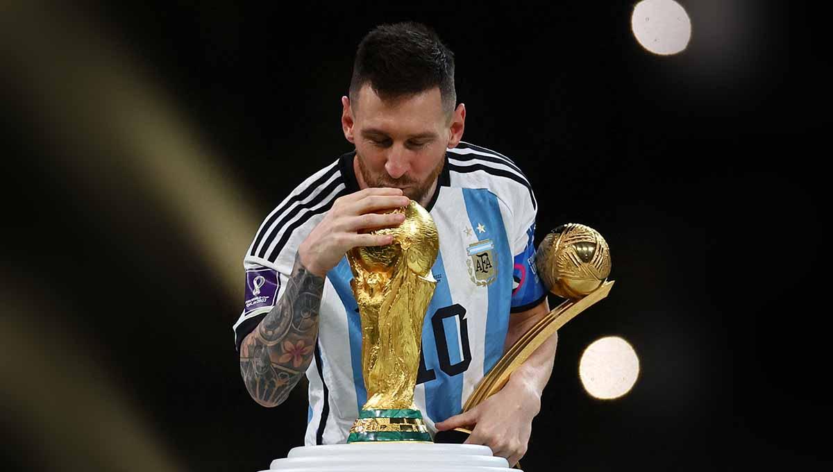 Lionel Messi mencium trofi Piala Dunia dan mendapat penghargaan Bola Emas Piala Dunia 2022. (Foto: REUTERS/Kai Pfaffenbach) - INDOSPORT