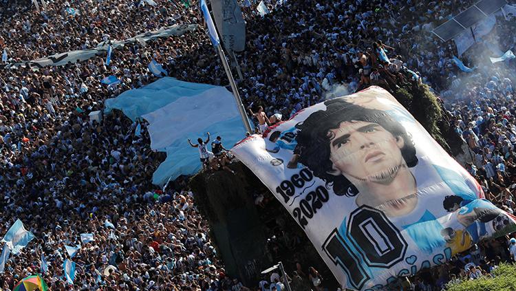 Pendukung timnas Argentina merayakan gelar Piala Dunia 2022 dengan membentangkan poster besar bergambar Diego Maradona. - INDOSPORT