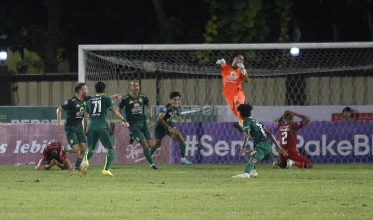 Kiper Persebaya Ernando Ari menggagalkan tendangan penalti pemain Arema FC di laga tunda Liga 1 antara Persebaya Surabaya vs Arema FC di Stadion PTIK, Jakarta, Selasa (11/04/23).