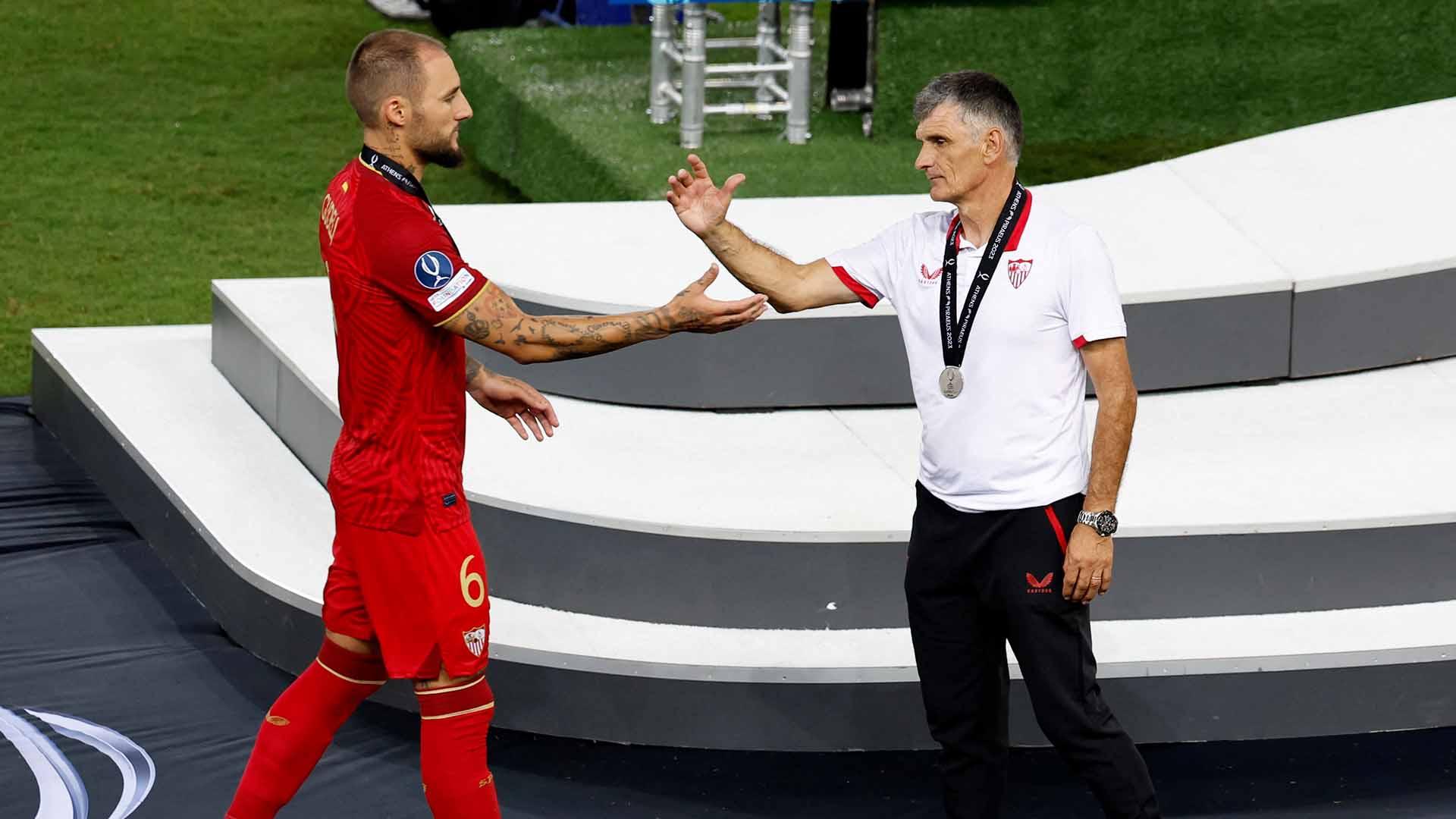 Pemain Sevilla, Nemanja Gudelj berjabat tangan dengan pelatih Jose Mendilibar usai pertandingan melawan Manchester City pada laga Piala Super UEFA 2023. (Foto: REUTERS/Louiza Vradi)