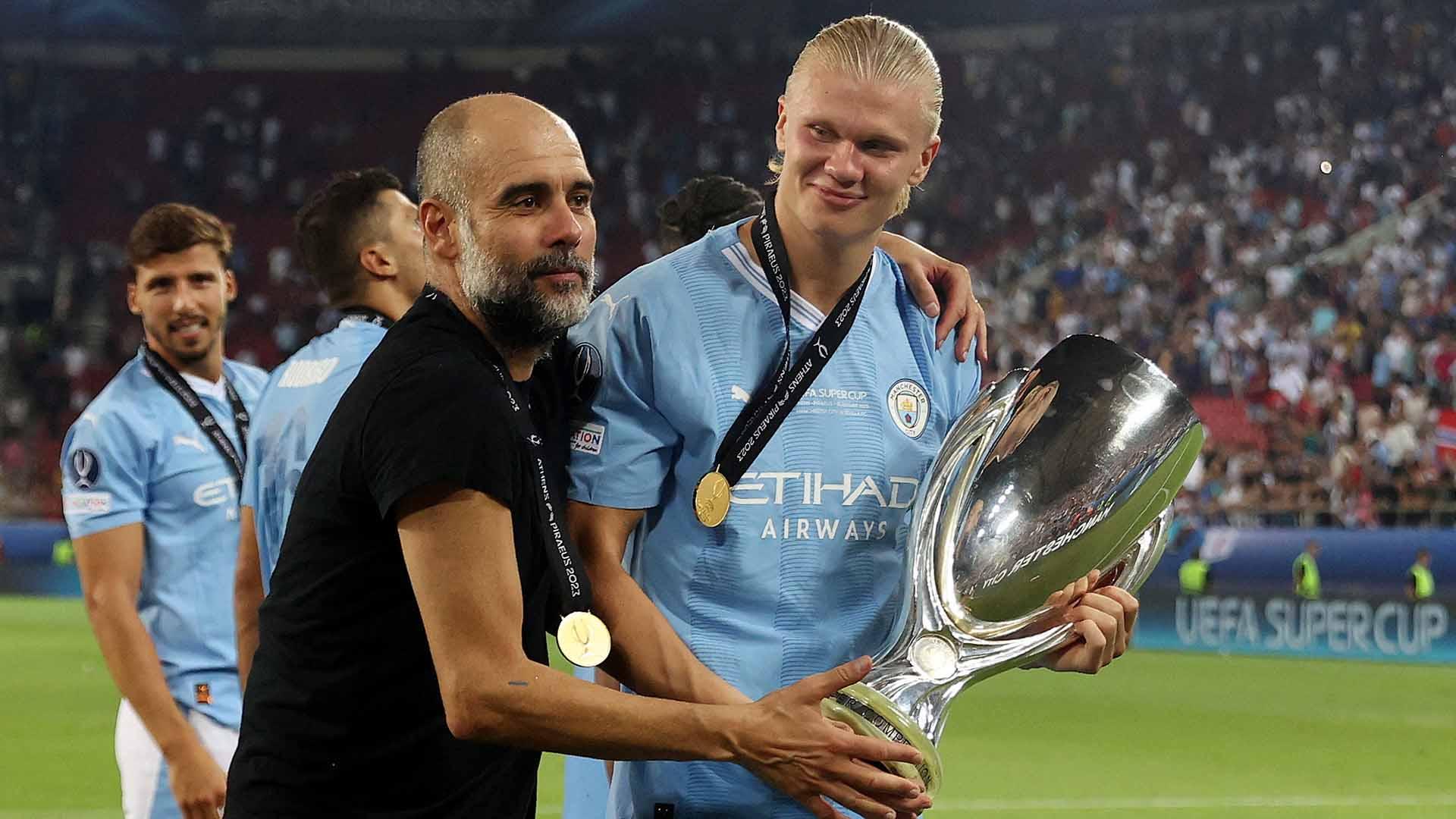 Selebrasi pemain Manchester City, Erling Haaland dengan pelatih Pep Guardiola dengan trofi usai memenangkan pertandingan melawan Sevilla pada laga Piala Super UEFA 2023. (Foto: REUTERS / Alkis Konstantinidis)