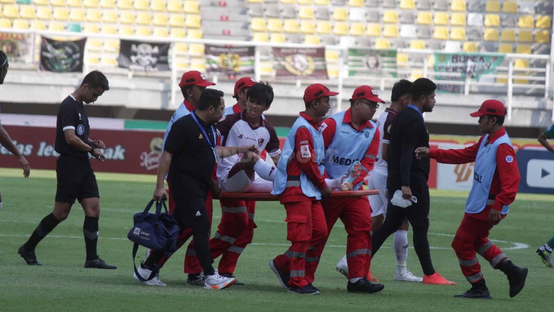 Pemain PSM Makassar Muh. Rizky Eka Pratama ditandu keluar lapangan karena mengalami cedera pada pekan kedelapan laga Liga 1 di Stadion Gelora Bung Tomo, Jumat (18/08/23). (Foto: Fitra Herdian/INDOSPORT)