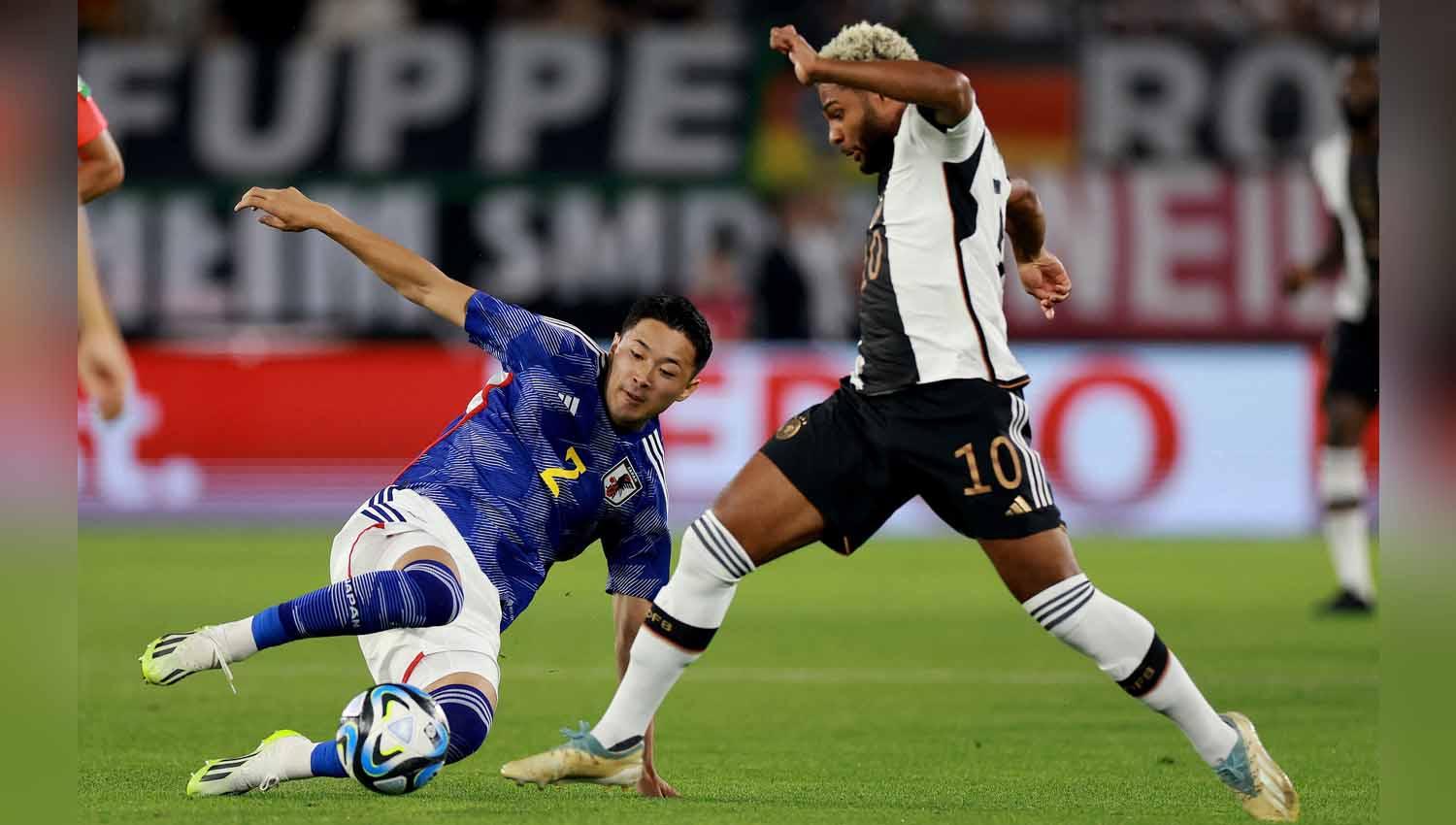 Pemain Jepang Yukinari Sugawara lakukan sleding kepada pemain Jerman Serge Gnabry pada laga Persahabatan. (Foto: REUTERS/Lisi Niesner) - INDOSPORT