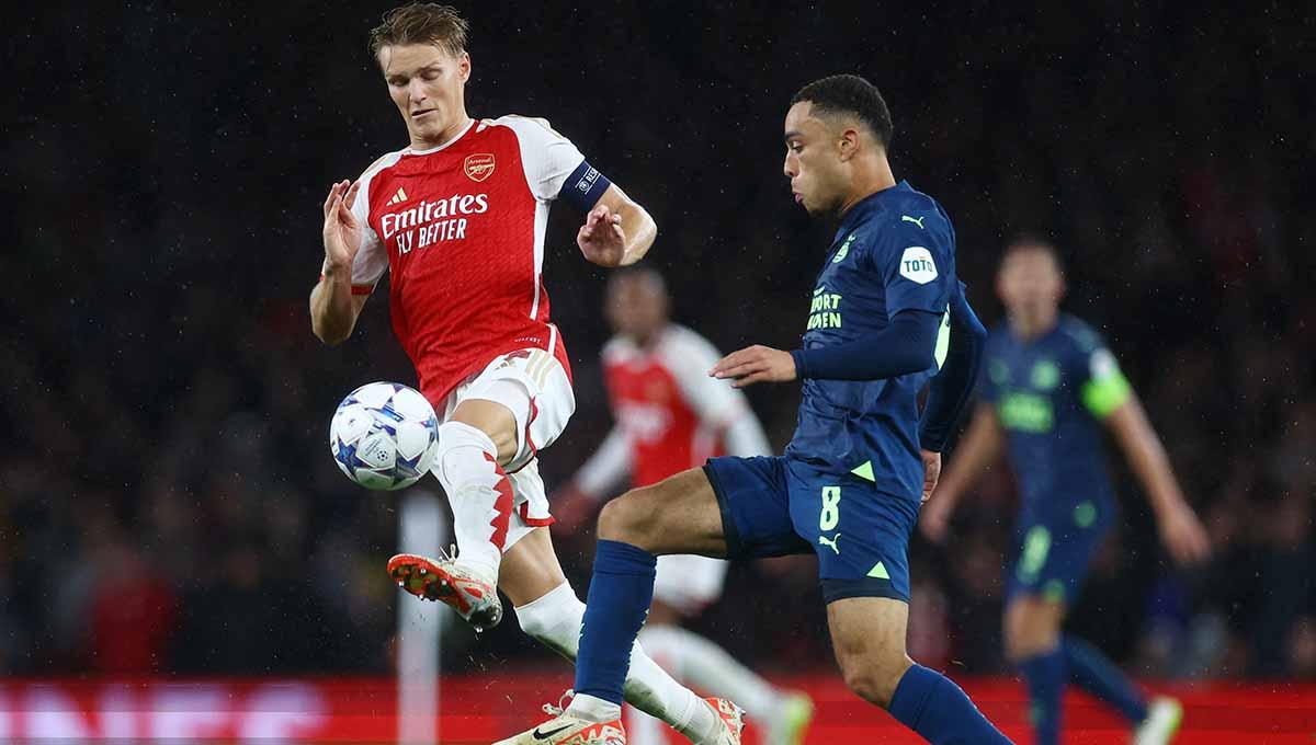 Pemain Arsenal, Martin Odegaard berusaha merebut bola dengan pemain PSV Eindhoven di Liga Champions.