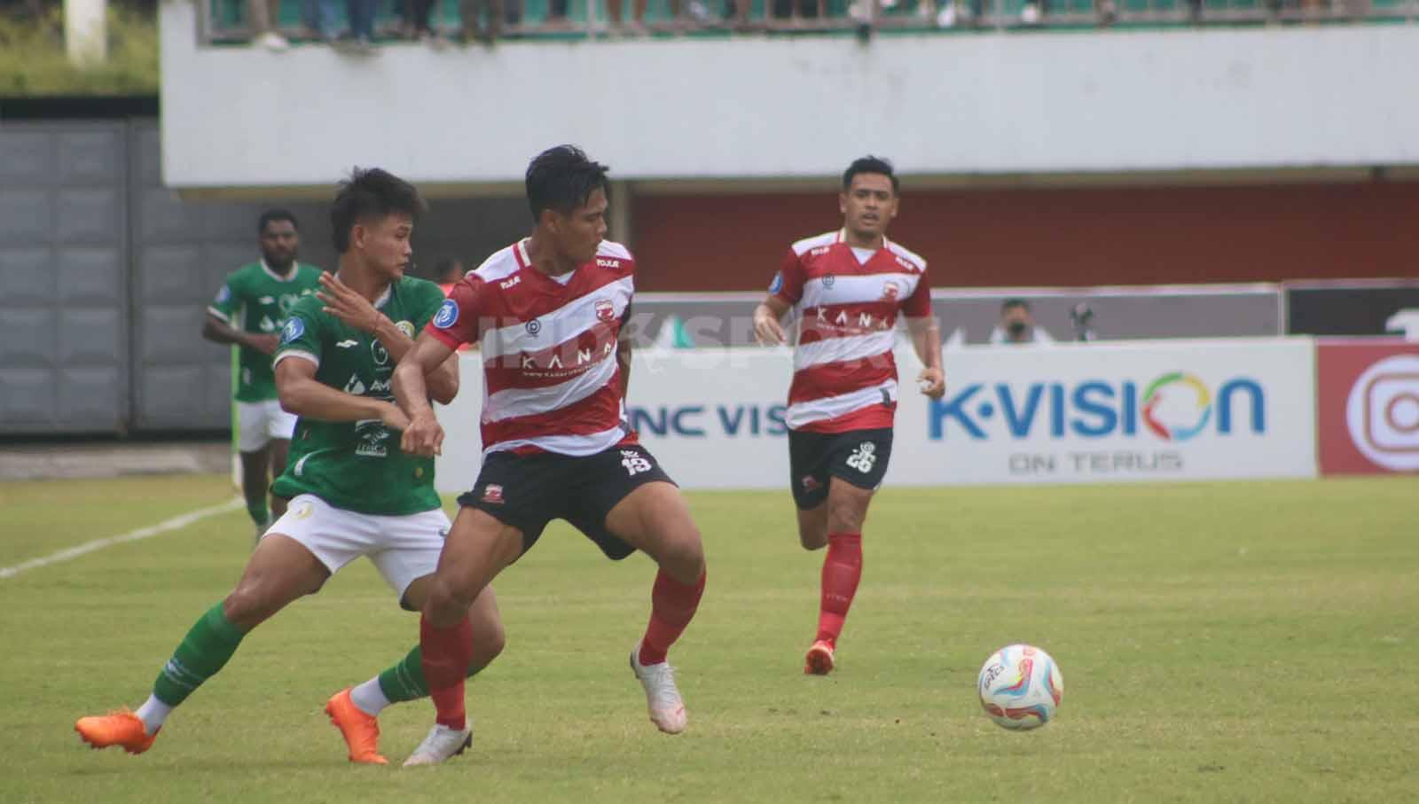 Bek Madura United, Fachrudin Aryanto, berusaha mengamankan bola dari kejaran Hokky Caraka  dalam laga pekan ke-13 Liga 1 2023-2024 di Stadion Maguwoharjo, Minggu (24/9/23).