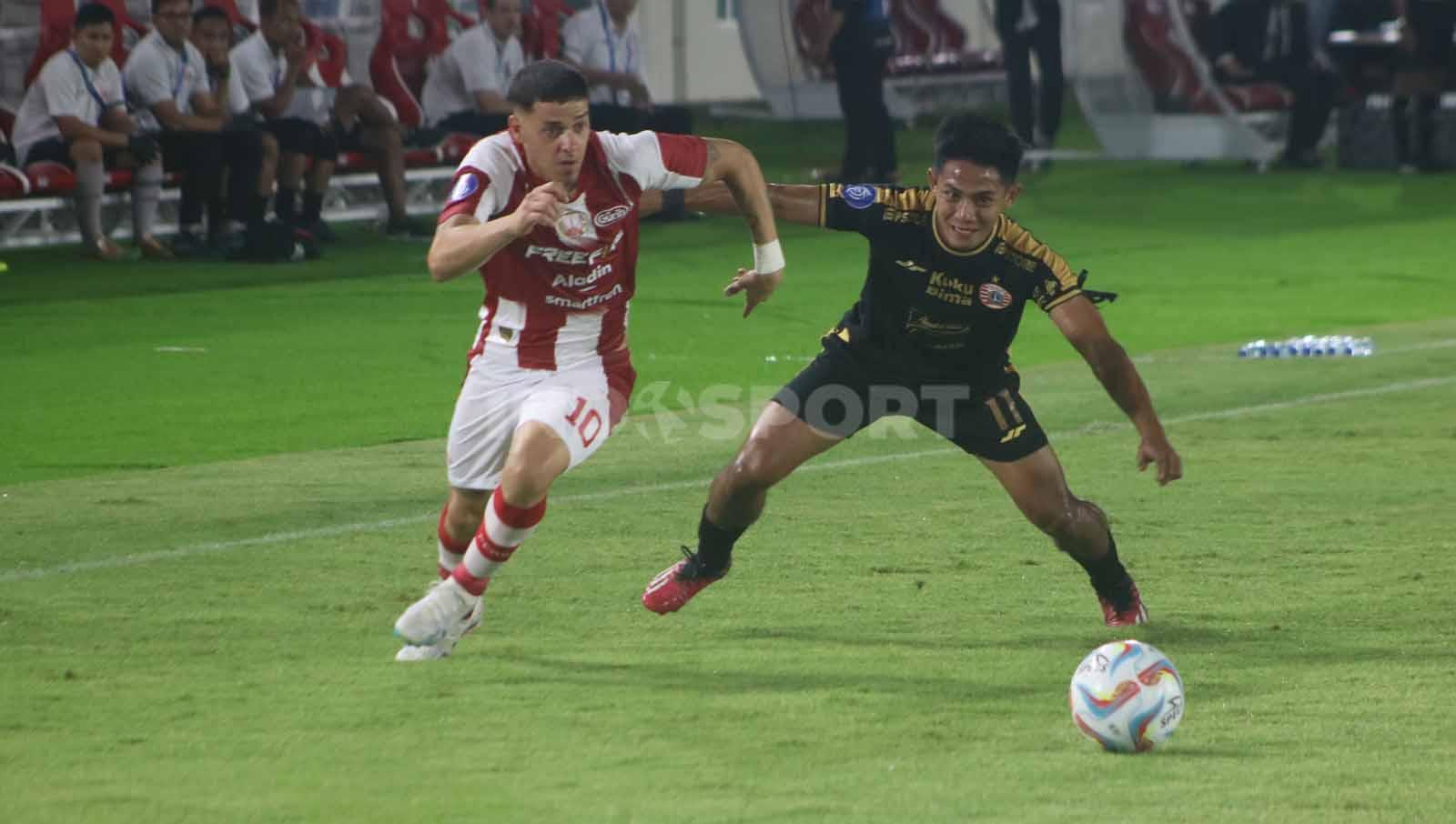 Bek Persija, Firza Andika, berusaha menutup pergerakan gelandang Persis Solo, Alexis Messidoro, dalam laga pekan ke-14 Liga 1 2023-2024, Sabtu (30/9/23). (Foto: Nofik Lukman Hakim/INDOSPORT)