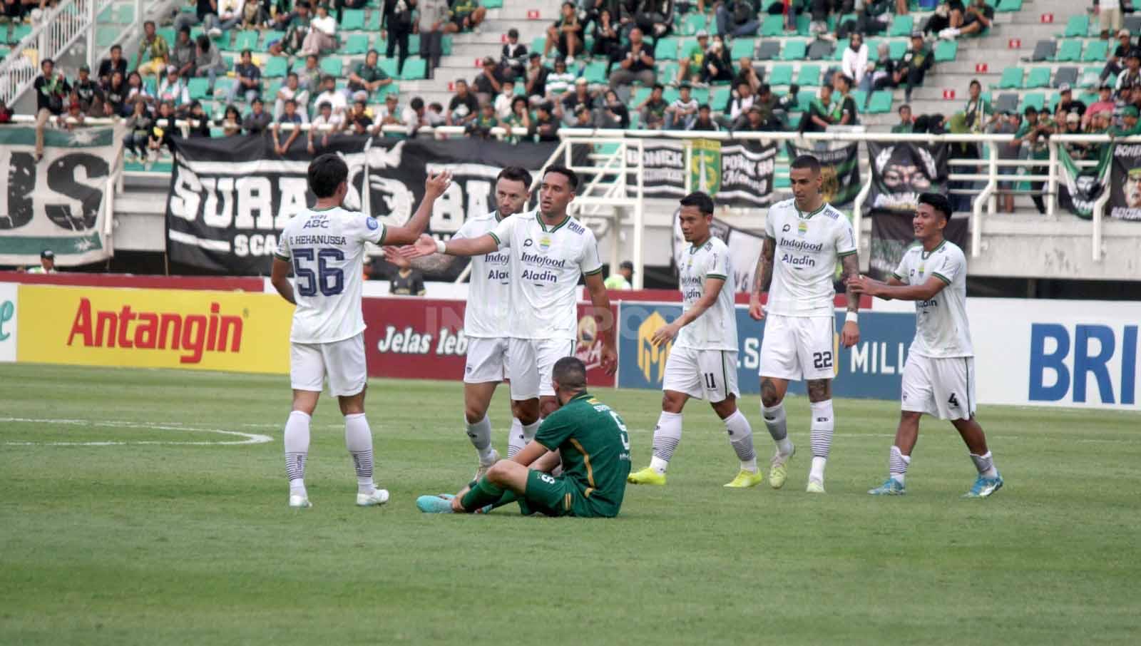 Dua potret berbeda, pemain Persebaya, Dusan Stevanovic meratapi kekalahan Persebaya dan para pemain Persib Bandung merayakan kemenangan pada pekan ke-15 laga BRI Liga 1 di Stadion Gelora Bung Tomo, (07/10/23). (Foto: Fitra Herdian/INDOSPORT)