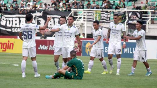 Dua potret berbeda, pemain Persebaya, Dusan Stevanovic meratapi kekalahan Persebaya dan para pemain Persib Bandung merayakan kemenangan pada pekan ke-15 laga BRI Liga 1 di Stadion Gelora Bung Tomo, (07/10/23). (Foto: Fitra Herdian/INDOSPORT)