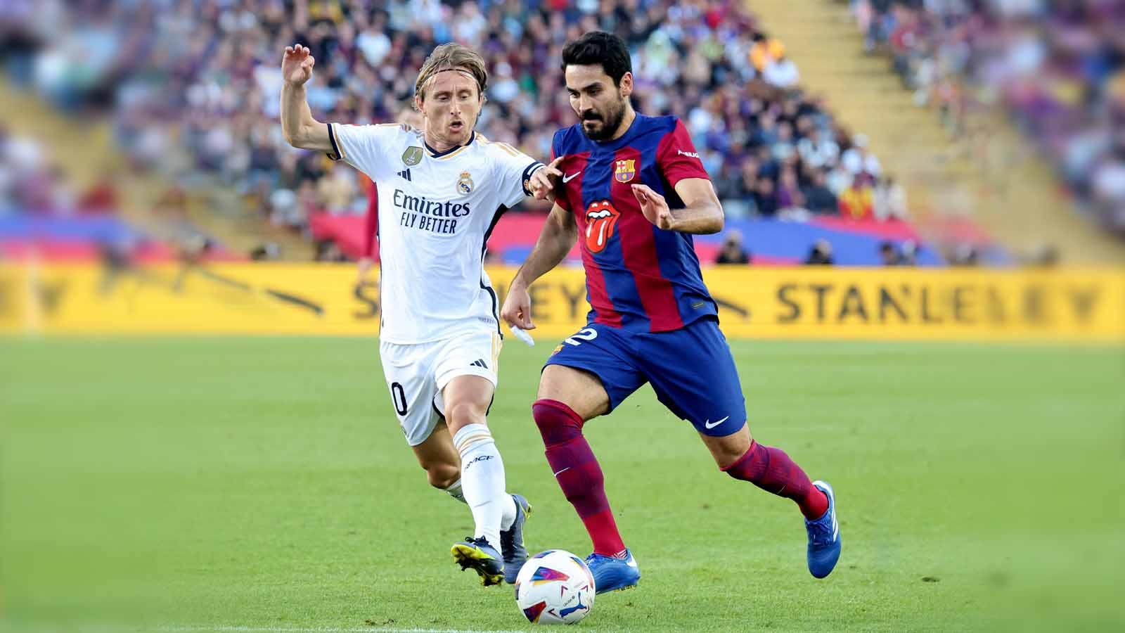 Luka Modric berebut bola saat dengan Ilkay Gundogan pada laga LaLiga Spanyol di Stadion Olímpic Lluís Companys (Barcelona), Sabtu (28/10/23). (Foto: REUTERS/Nacho Doce)