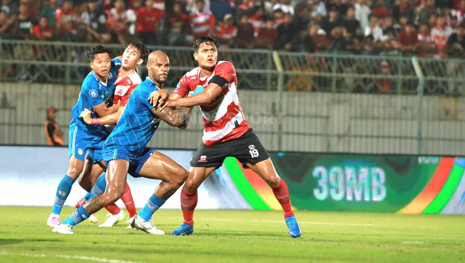 Pemain Madura United, Fachruddin Wahyudi berduel untuk merebutkan bola dengan pemain Persib David Da Silva.