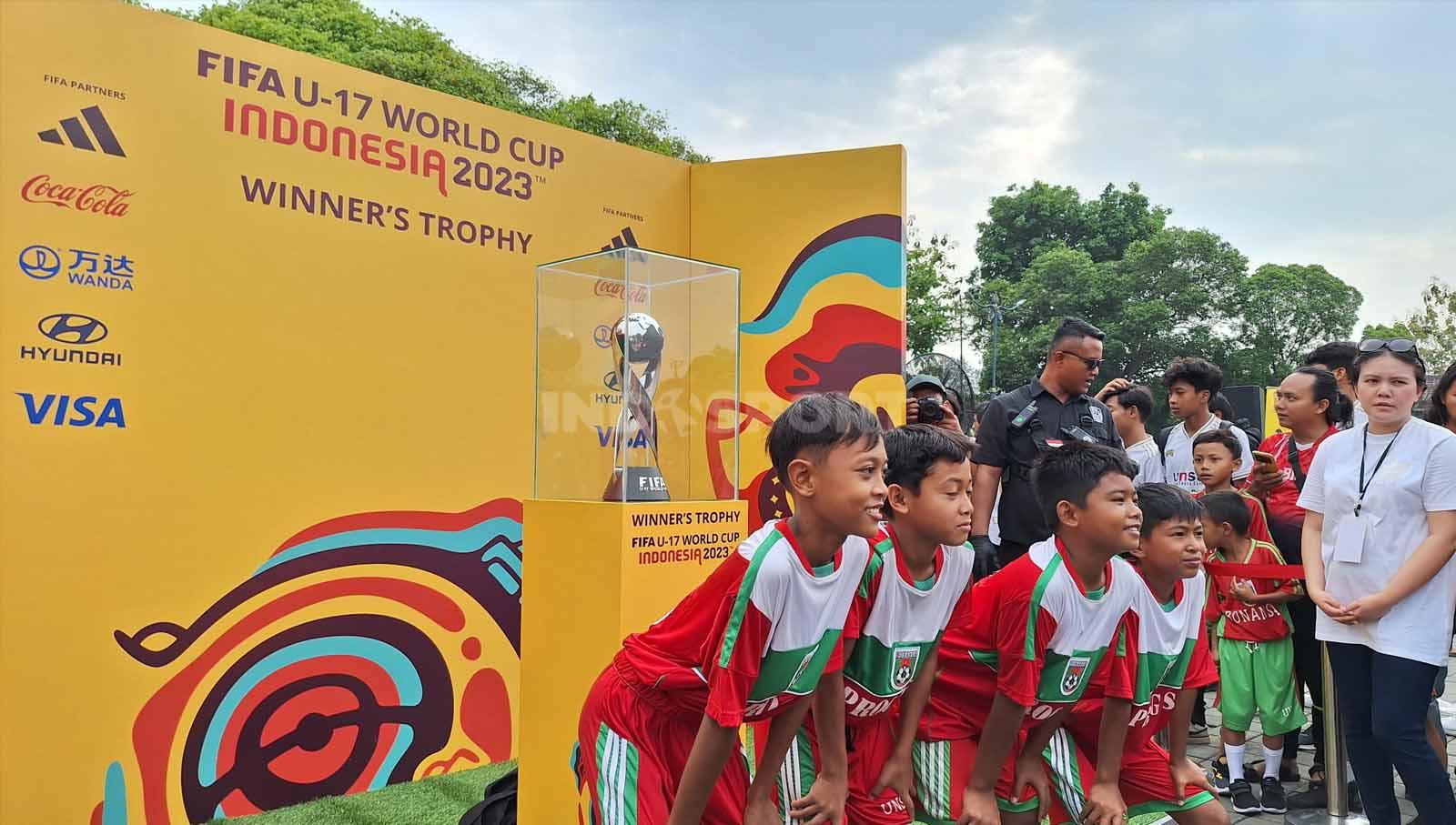 Anak-anak Sekolah Sepak Bola (SSB) Bonanza Solo saat berpose dengan trofi Piala Dunia U-17 di Pura Mangkunegaran, Minggu (5/11/23).