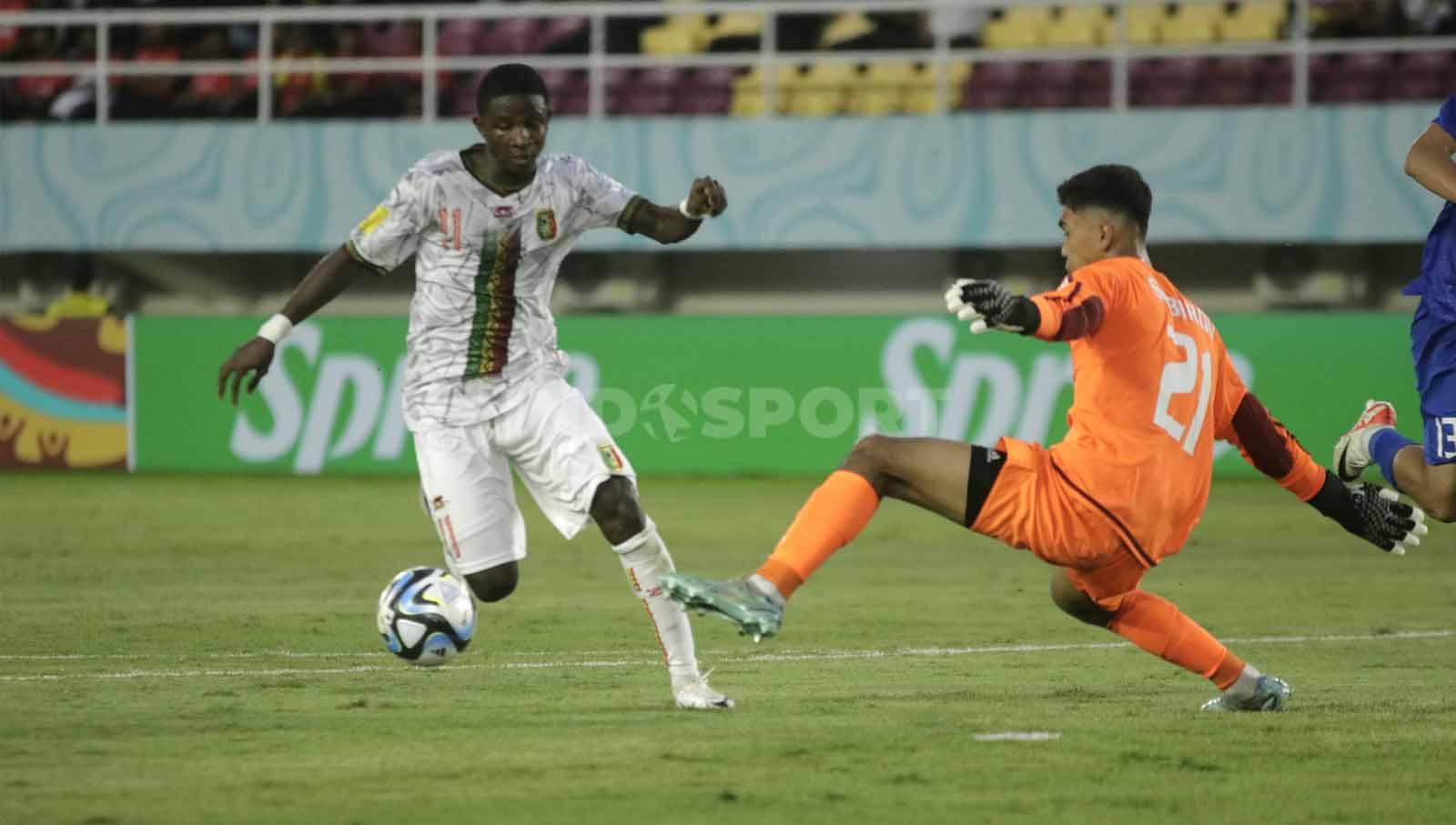 Kiper Uzbekistan U-17, Muhammad Yusuf Sobirov berusaha menutup pergerakan penyerang Mali U-17, Ibrahim Kanate, dalam pertandingan Piala Dunia U-17 2023 grup B di Stadion Manahan Solo, Jumat (10/11/23. Nofik Lukman Hakim/INDOSPORT