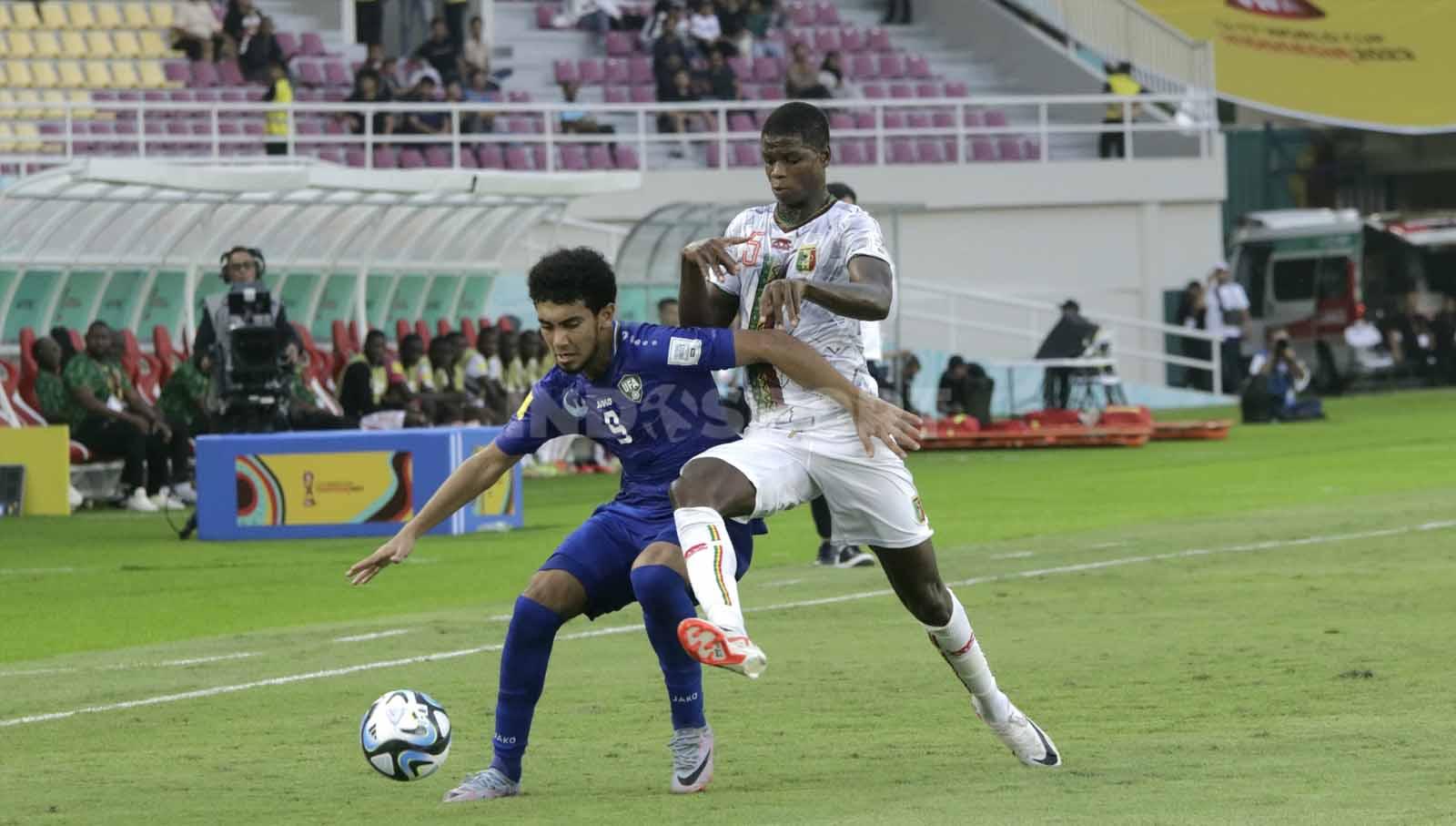 Penyerang Uzbekistan U-17, Amiebek Saidov, menjaga bola yang coba direbut bek Mali u-17, Baye Coulibaly,  dalam pertandingan Piala Dunia U-17 2023 grup B di Stadion Manahan Solo, Jumat (10/11/23. Nofik Lukman Hakim/INDOSPORT