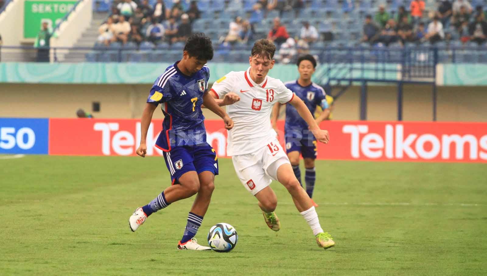 Gelandang Timans Jepang U-17, Nakajima Yotaro dan gelandang Polandia U-17, Lyczko berebut bola pada laga perdana Grup D Piala Dunia U-17 2023 di Stadion Si Jalak Harupat, Kabupaten Bandung, Sabtu (11/11/23). Arif Rahman/INDOSPORT