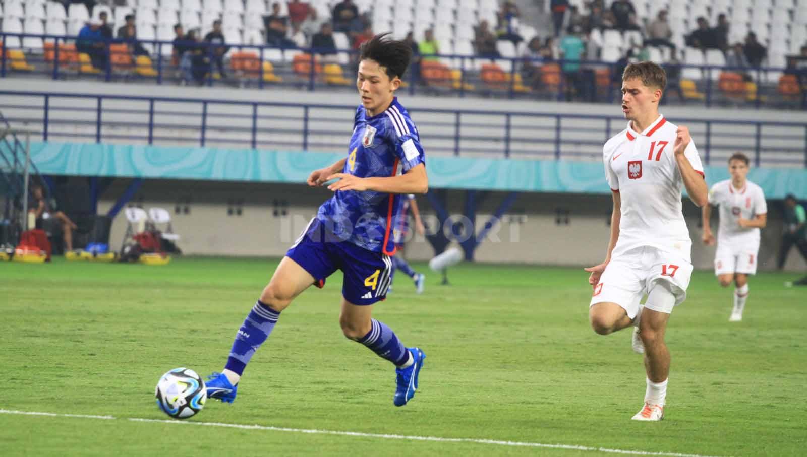 Bek Timnas Jepang U-17, Tsuchiya mengamankan bola dari kejaran pemain Polandia U-17, Huras Mike, pada laga perdana Grup D Piala Dunia U-17 2023 di Stadion Si Jalak Harupat, Kabupaten Bandung, Sabtu (11/11/23). Arif Rahman/INDOSPORT