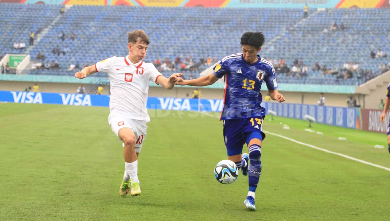 Gelandang Timnas Jepang U-17, Yoshinaga Yumeki berebut bola dengan Lyczko Szymon pada laga perdana Grup D Piala Dunia U-17 2023 di Stadion Si Jalak Harupat, Kabupaten Bandung, Sabtu (11/11/23). Arif Rahman/INDOSPORT
