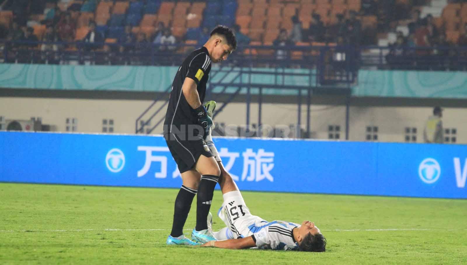 Penjaga gawang Argentina U-17, Diaz Froilan membantu rekannya Gimenez Juan yang mengalami masalah di kakinya, saat menghadapi Senegal U-17 pada pertandingan Grup D Piala Dunia U-17 2023 di Stadion Si Jalak Harupat, Kabupaten Bandung, Sabtu (11/11/23). Arif Rahman/INDOSPORT