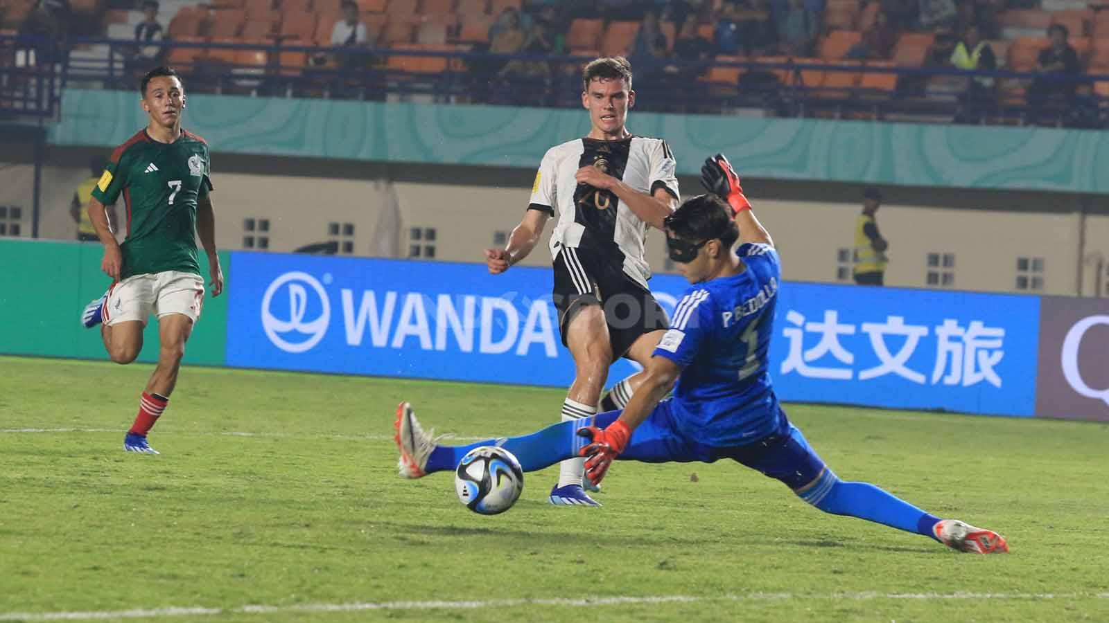 Bola sepekan striker Jerman U-17, Ramsak Robert, tidak dapat diantisipasi kiper Meksiko U-17, Bedolla Paolo pada pertandingan Grup F Piala Dunia U-17 2023 di Stadion Si Jalak Harupat, Kabupaten Bandung, Minggu (12/11/23). (Foto: Arif Rahman/INDOSPORT)