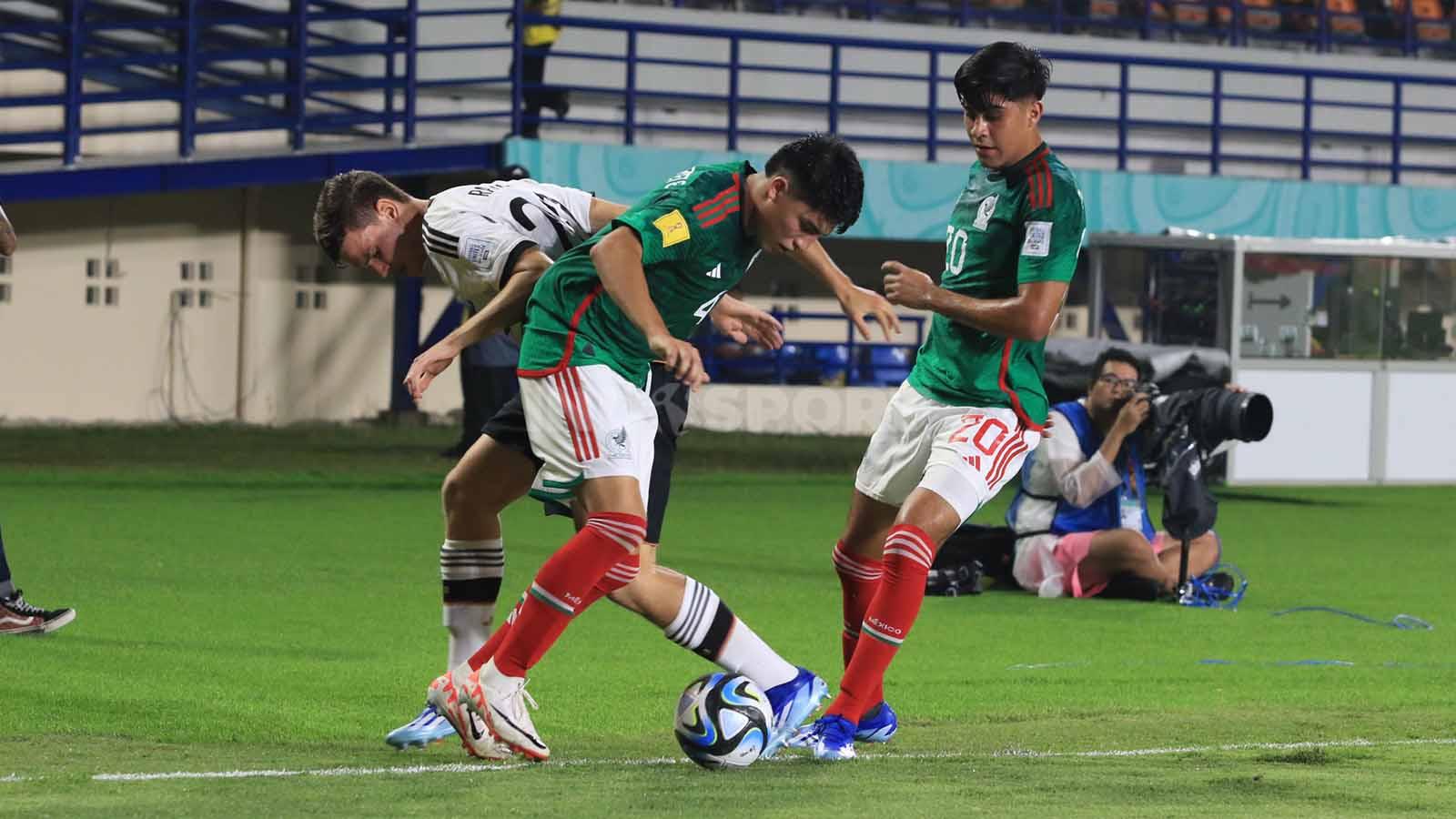 Striker Jerman U-17, Ramsak Robert dikawal ketat bek Meksiko U-17, Navarrete dan Valenzuela Francisco pada pertandingan Grup F Piala Dunia U-17 2023 di Stadion Si Jalak Harupat, Kabupaten Bandung, Minggu (12/11/23). (Foto: Arif Rahman/INDOSPORT)