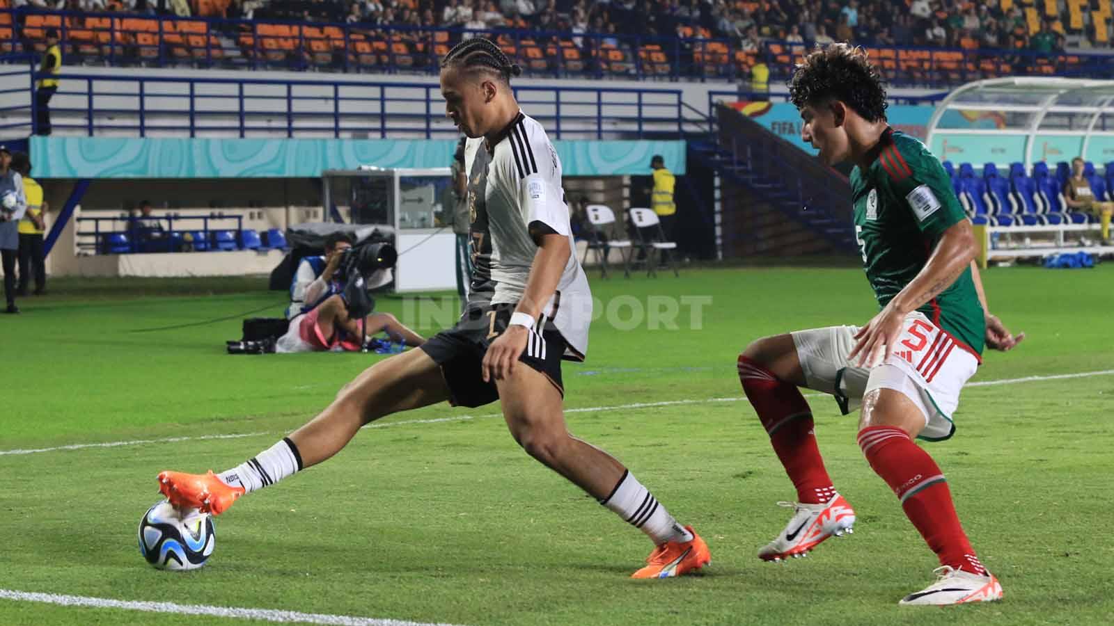 Pemain Jerman U-17, Da Silava Moreira Eric, dikawal ketat bek Meksiko U-17, Romero Javen, pada pertandingan Grup F Piala Dunia U-17 2023 di Stadion Si Jalak Harupat, Kabupaten Bandung, Minggu (12/11/23). (Foto: Arif Rahman/INDOSPORT)