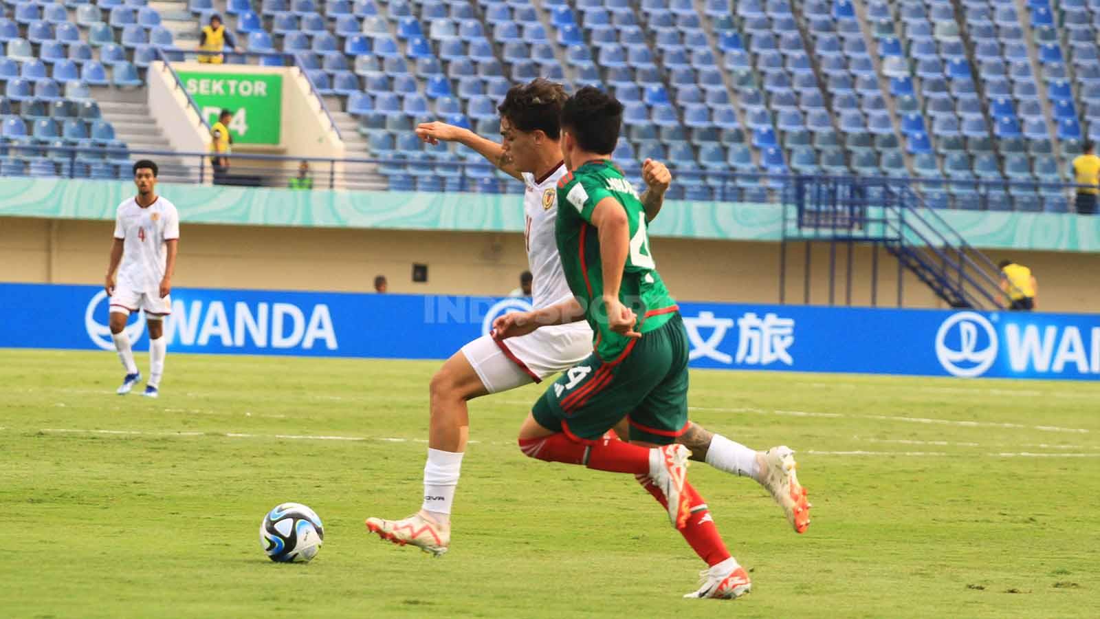 Gelandang Timnas Venezuela U-17, Arango Juan, menggiring bola dan dibayangi pemain Mexico U-17, pada pertandingan Grup F Piala Dunia U-17 2023 di Stadion Gelora Bandung Lautan Api (GBLA), Kota Bandung, Rabu (15/11/23).