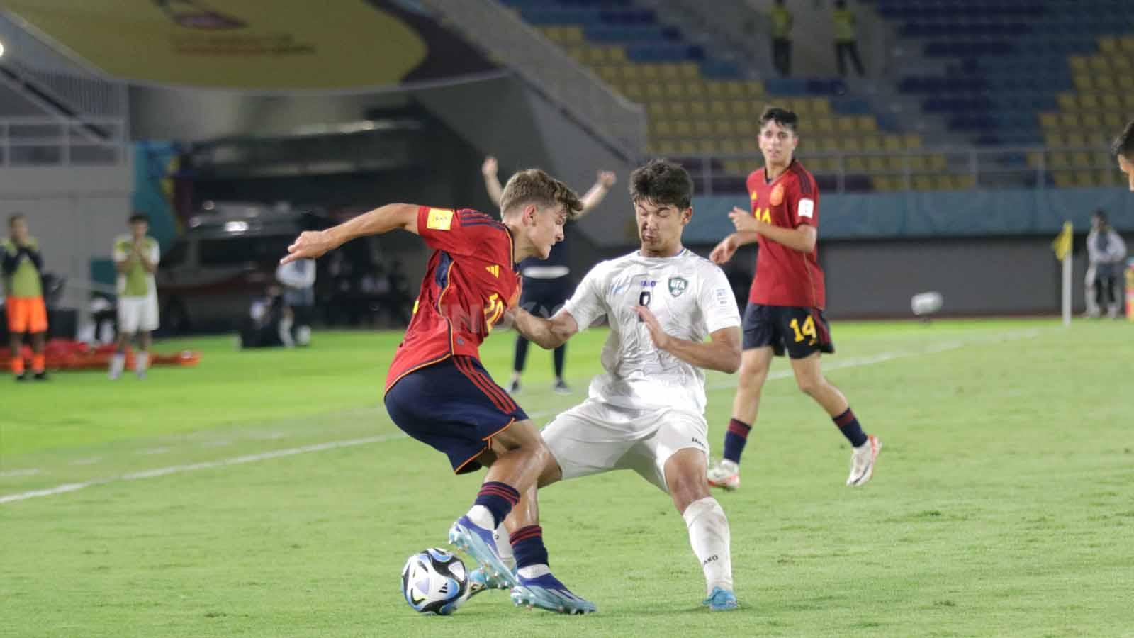 Gelandang Spanyol, Juan Hernandez, berusaha melewati gelandang Uzbekistan, Bekhuz Shukurullaev, dalam pertandingan fase grup B Piala Dunia U-17 2023 di Stadion Manahan Solo, Kamis (16/11/23). (Foto: Nofik Lukman Hakim/INDOSPORT)