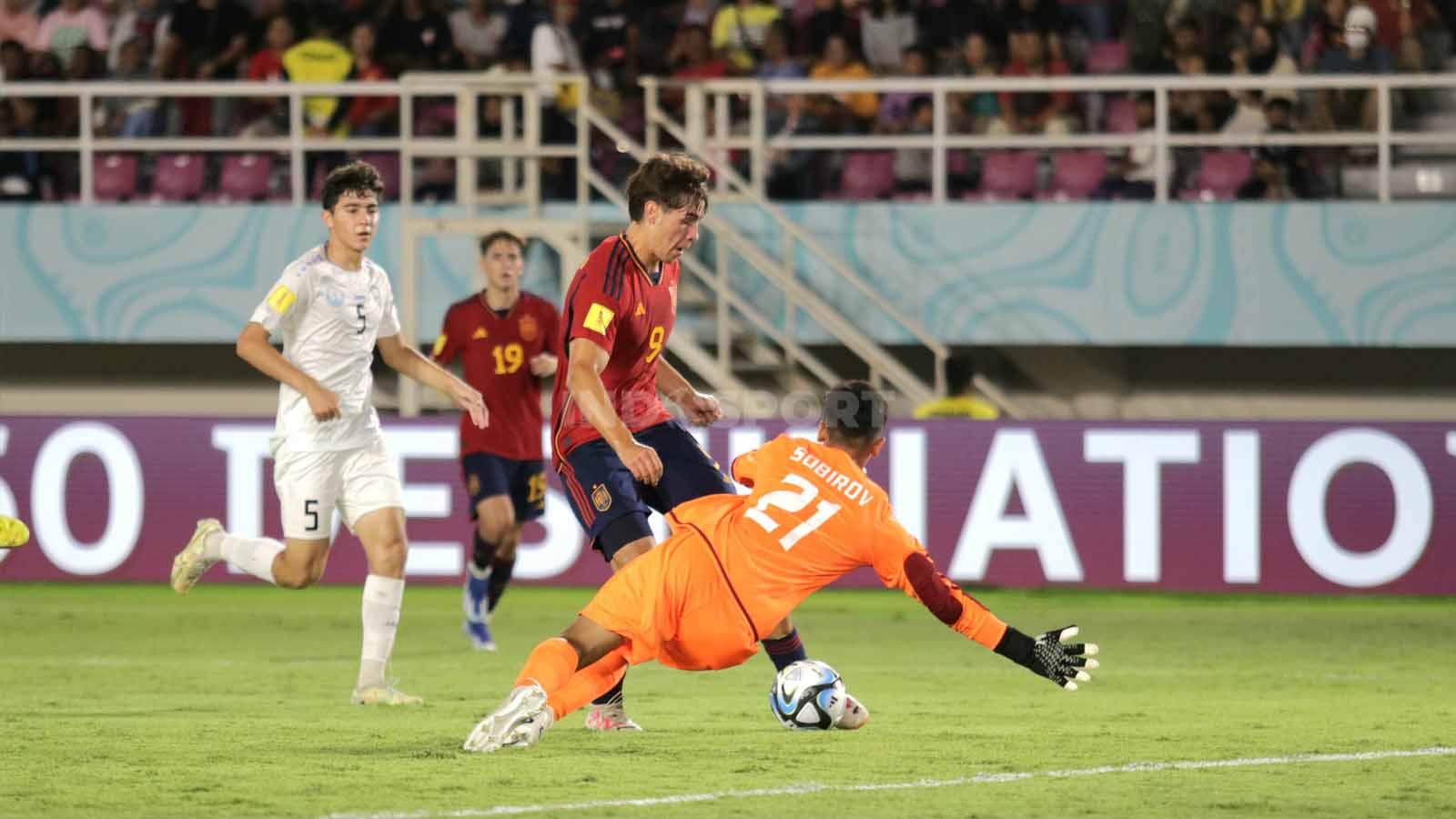 Kiper Uzbekistan, Muhammad Yusuf Sobirov, berusaha menutup ruang tembak penyerang Spanyol, Marc Guiu,  dalam pertandingan fase grup B Piala Dunia U-17 2023 di Stadion Manahan Solo, Kamis (16/11/23). (Foto: Nofik Lukman Hakim/INDOSPORT)