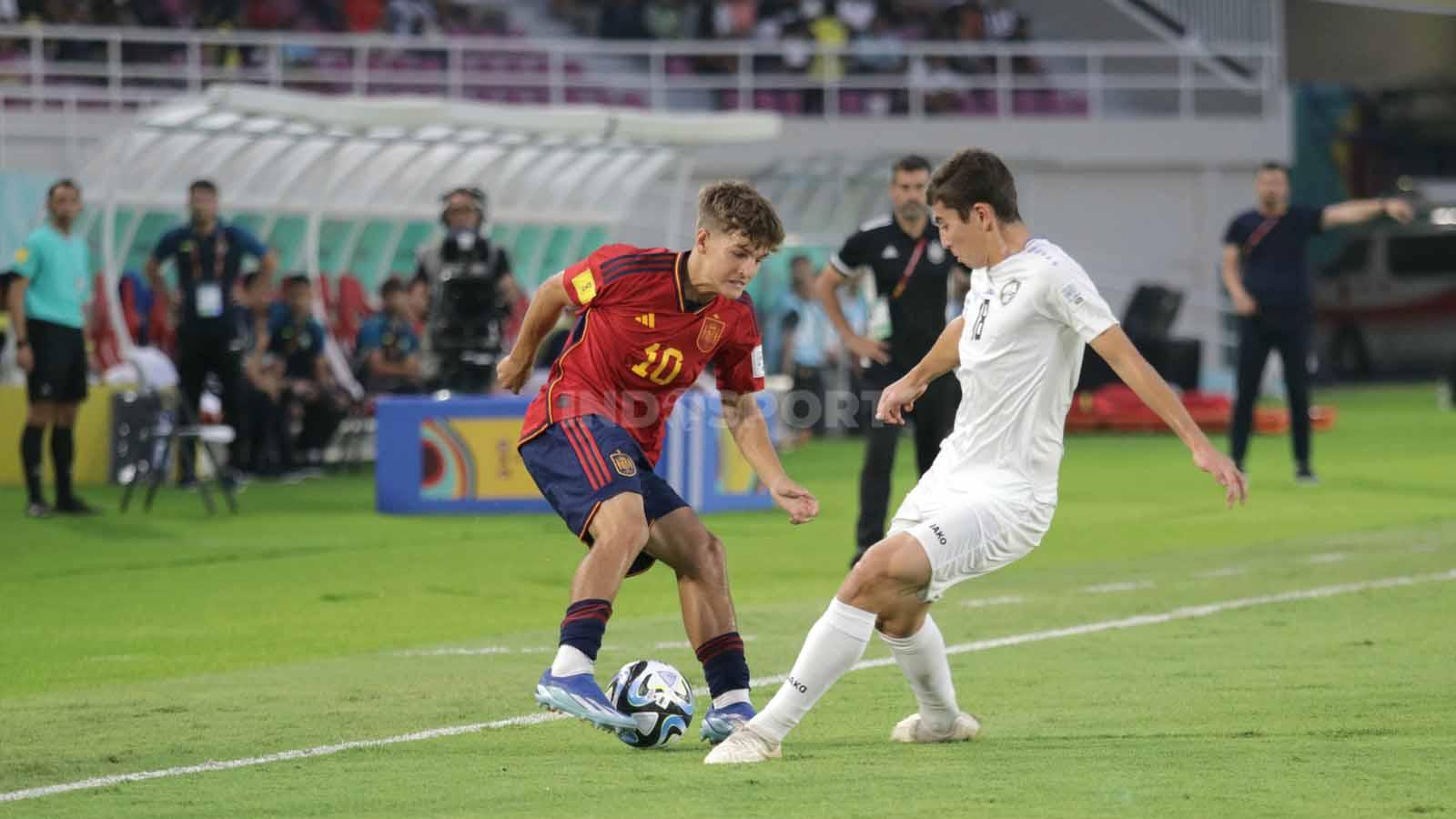 Gelandang Spanyol, Juan Hernandez, saat berusaha melewati pemain Uzbekistan  dalam pertandingan fase grup B Piala Dunia U-17 2023 di Stadion Manahan Solo, Kamis (16/11/23). (Foto: Nofik Lukman Hakim/INDOSPORT)