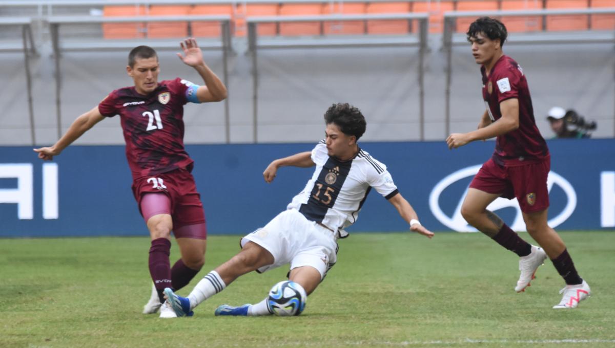 Pemain Jerman, Justin Von Der Hitz melakukan tackle ke arah pemain Venezuela, Nicola Profeta pada laga ketiga fase grup F Piala Dunia U-17 2023 di Stadion JIS, Sabtu (18/11/23).