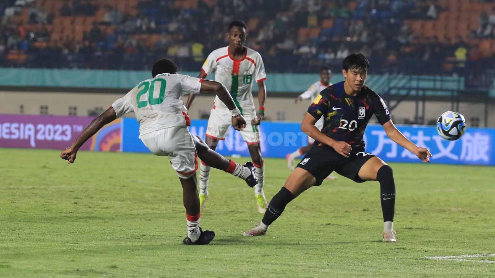 Gelandang Burkina Faso U-17, Ouedrago Emmanuel  mencoba melepaskan tendangan ke gawang Korea Selatan U-17, pada pertandingan terakhir Grup E Piala Dunia U-17 2023 di Stadion Si Jalak Harupat, Kabupaten Bandung, Sabtu (18/11/23). Arif Rahman/INDOSPORT