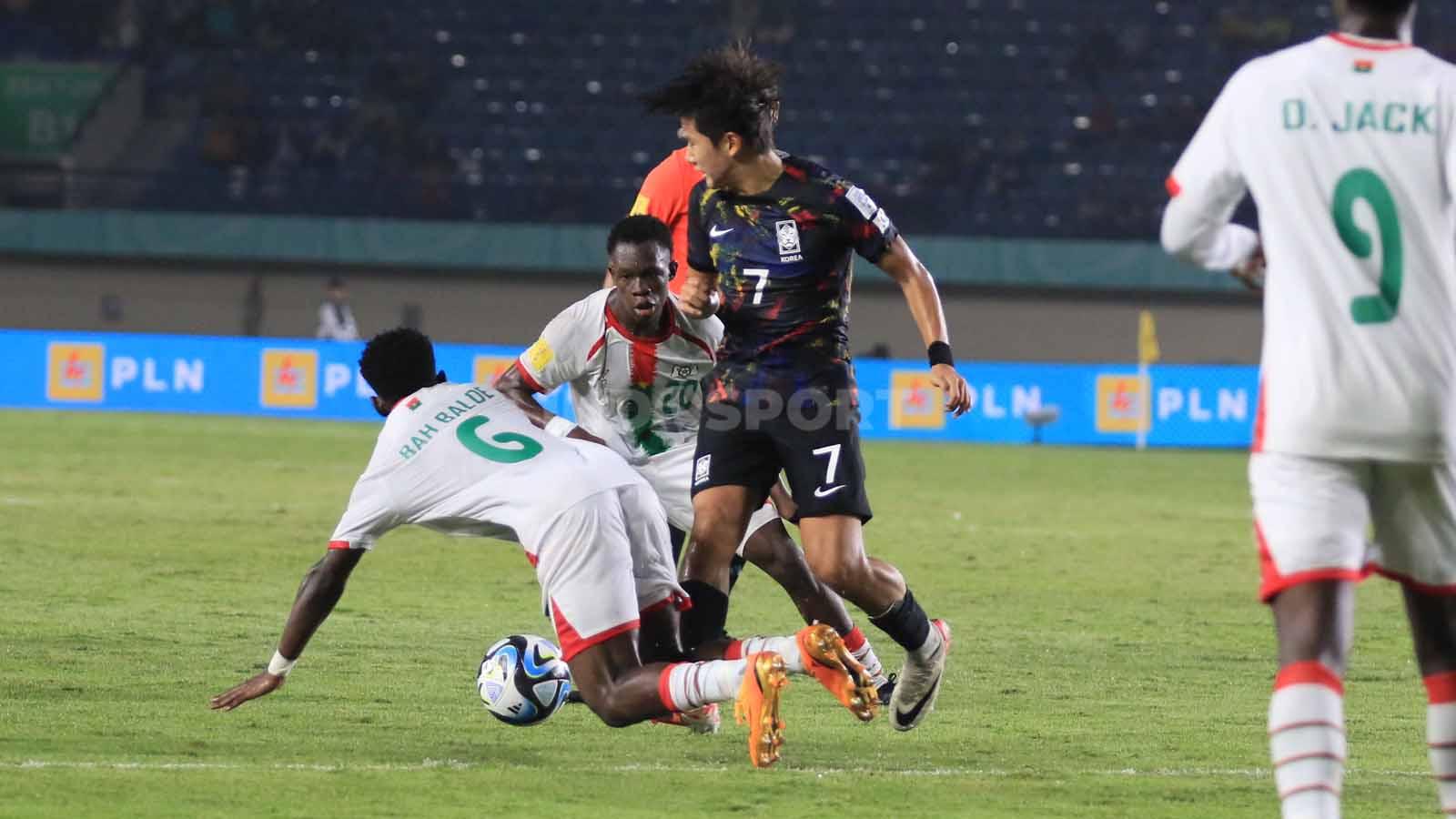 Gelandang Korea Selatan U-17, Yoon Doyong berebut bola dengan dua pemain Burkina Faso U-17 pada pertandingan terakhir Grup E Piala Dunia U-17 2023 di Stadion Si Jalak Harupat, Kabupaten Bandung, Sabtu (18/11/23). Arif Rahman/INDOSPORT