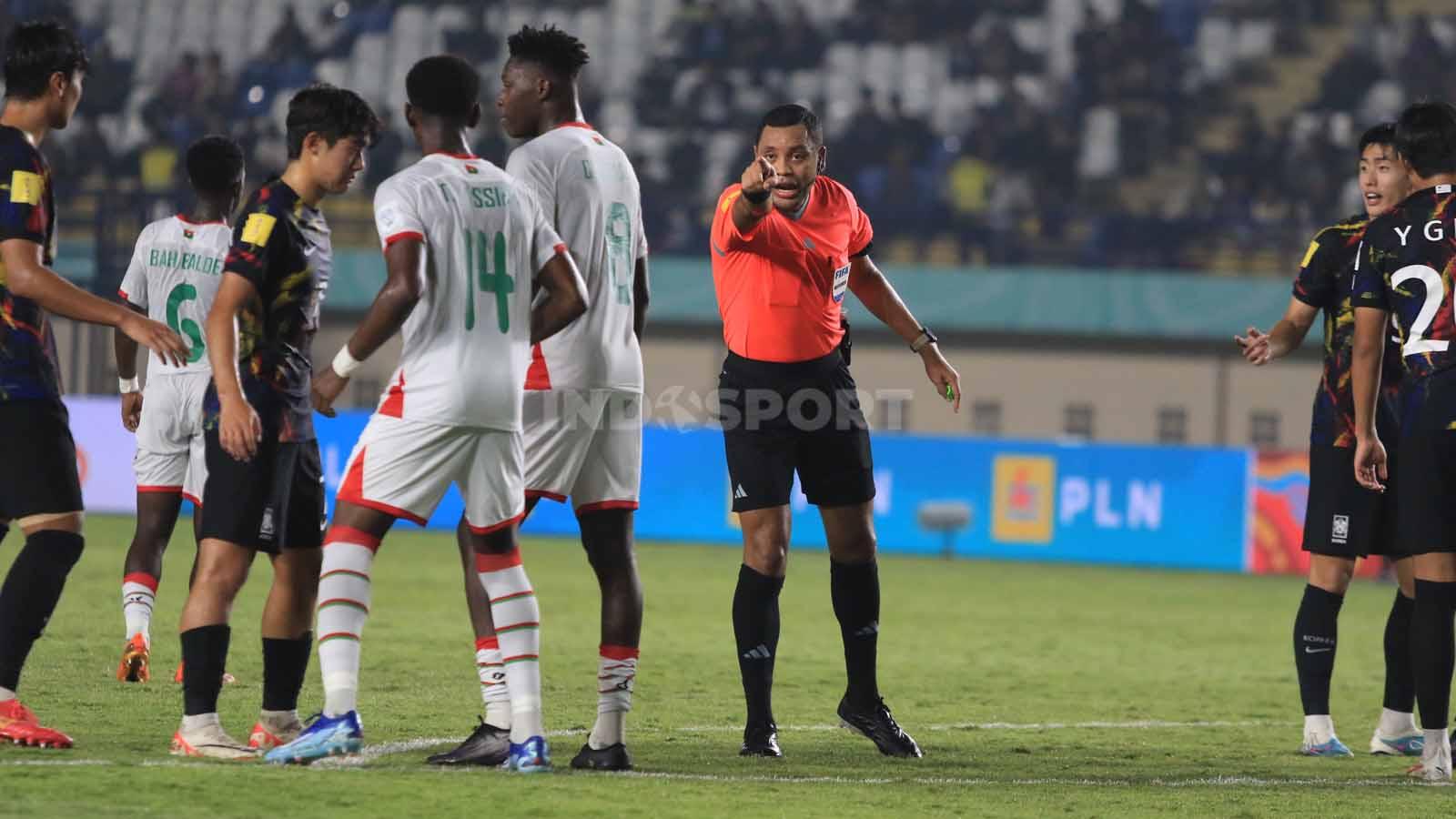Wasit Brown Selvin memberikan pengarahan kepada pemain saat laga Burkina Faso U-17 vs Korea Selatan U-17, pada pertandingan terakhir Grup E Piala Dunia U-17 2023 di Stadion Si Jalak Harupat, Kabupaten Bandung, Sabtu (18/11/23). Arif Rahman/INDOSPORT