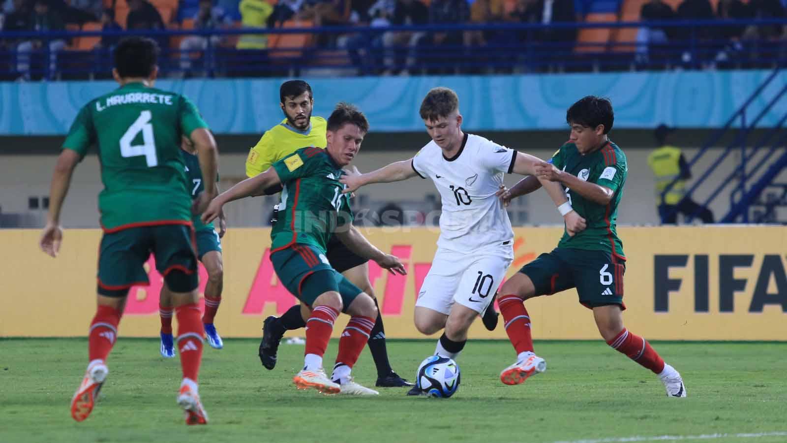 Striker Timnas Selandia Baru U-17, Adam Watson mencoba melewati pemain Meksiko U-17, pada pertandingan Grup F Piala Dunia U-17 2023 di Stadion Si Jalak Harupat, Kabupaten Bandung, Sabtu (18/11/23). Arif Rahman/INDOSPORT