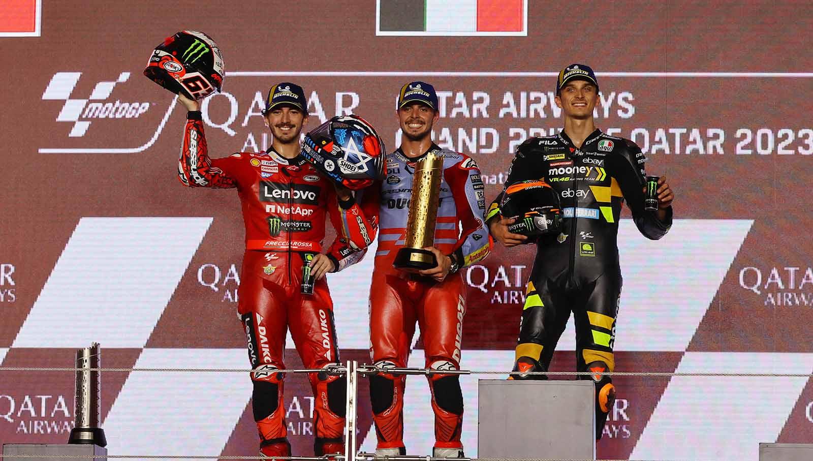 Fabio Di Giannantonio merayakan dengan trofi di podium pada posisi pertama bersama Francesco Bagnaia pada posisi kedua dan Luca Marini pada posisi ketiga di Sirkuit Internasional Lusail, Lusail, Qatar, Minggu (19/11/23). (Foto: REUTERS/Ibraheem Al Omari)