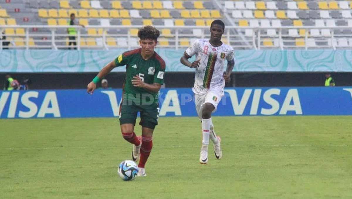 Javen Romero berusaha mempertahankan bola dari pemain Mali U-17 Ibrahim Diarra di babak 16 besar Piala Dunia U-17 di Stadion GBT, Selasa (21/11/23). (Foto: Fitra Herdian/INDOSPORT)