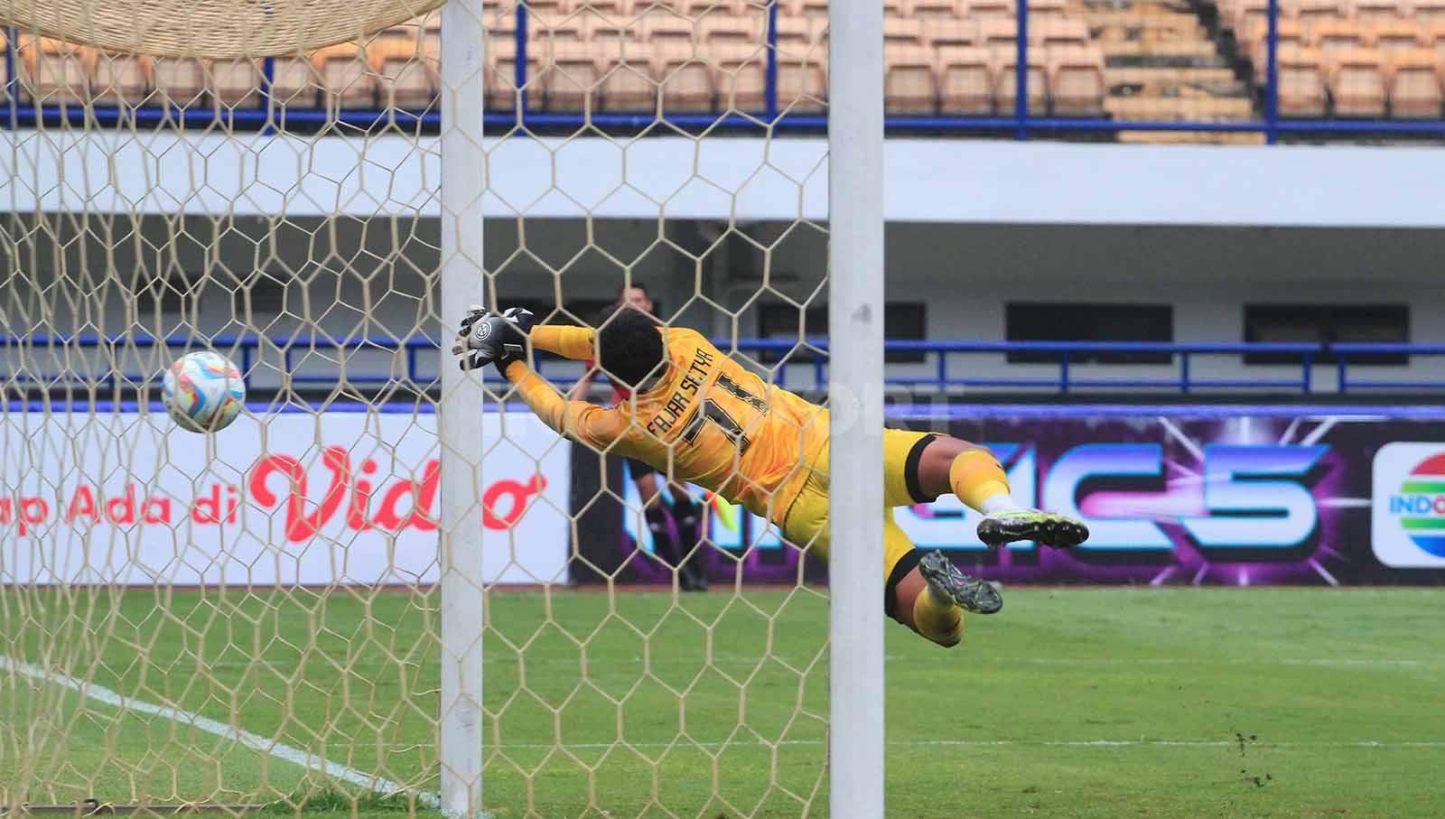 Penjaga gawang PSKC Cimahi, Fajar Setya gagal mengamankan bola hasil tendangan Kevy Syahertian Persikab Bandung pada pertandingan pekan ke-11 Liga 2 2023-2024 di Stadion GBLA, Kota Bandung, Minggu (26/11/23). (Foto: Arif Rahman/INDOSPORT)