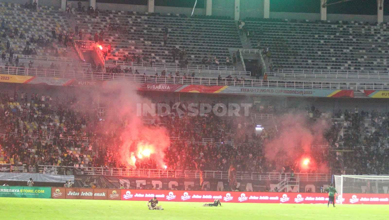 Flare menyala di Stadion GBT usai laga Persebaya vs Persis berakhir imbang 1-1 pada laga Liga 1 di Stadion di Gelora Bung Tomo, Rabu (13/12/23). (Foto: Fitra Herdian/INDOSPORT)