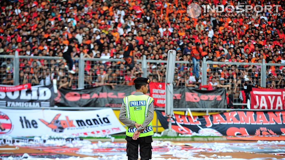 Seorang polisi terlihat siaga mengawasi Jakmania yang memenuhi Stadion Utama Gelora Bung Karno.