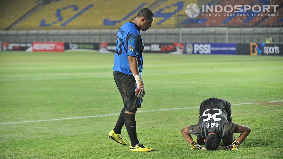 Penjaga gawang Persipura Piere F Kahol mencoba menghibur kiper Mitra Kukar Riki Pambudi setelah gagal mengamankan gawangnya dari sepakan penalti pemain Persipura.