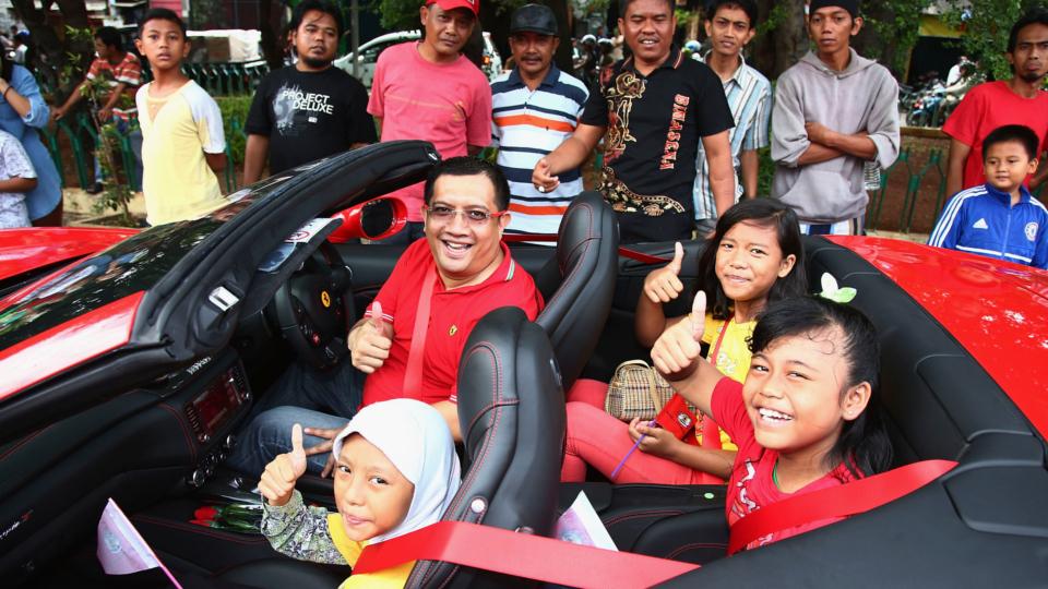 Anggota Ferrari Owners Club Indonesia berfoto bersama anak-anak warga Kelurahan Kebon Bawang, Tanjung Priok, Jakarta Utara, Minggu (18/01/15). - INDOSPORT