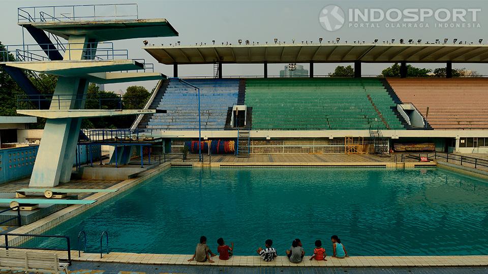 Tampak beberapa anak kecil tengah duduk di bibir kolam renang Senayan, Jakarta.