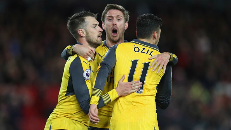 Ramsey (kiri), Koscielny (tengah), dan Ozil merayakan gol kedua Arsenal. Copyright: © Ian MacNicol / Stringer / Getty Images