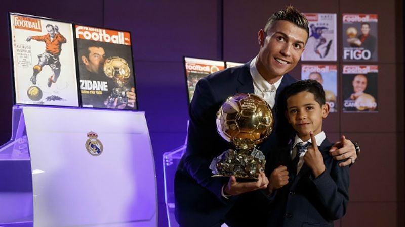 Cristiano Ronaldo (kiri) bersama dengan sang anak saat berpose dengan Ballon d'Or. Copyright: © Angel Martinez / Contributor / Getty Images